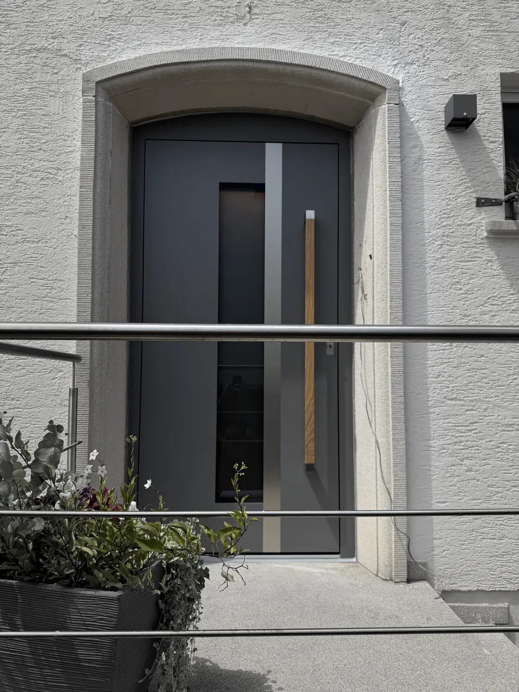 Anthrazitfarbene einflügelige Haustür im Rundbogen-Portal