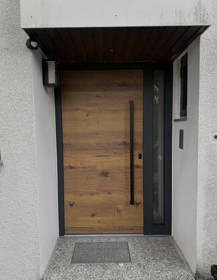 Aluminium-Tür in Holzdekor unter Holzvordach
