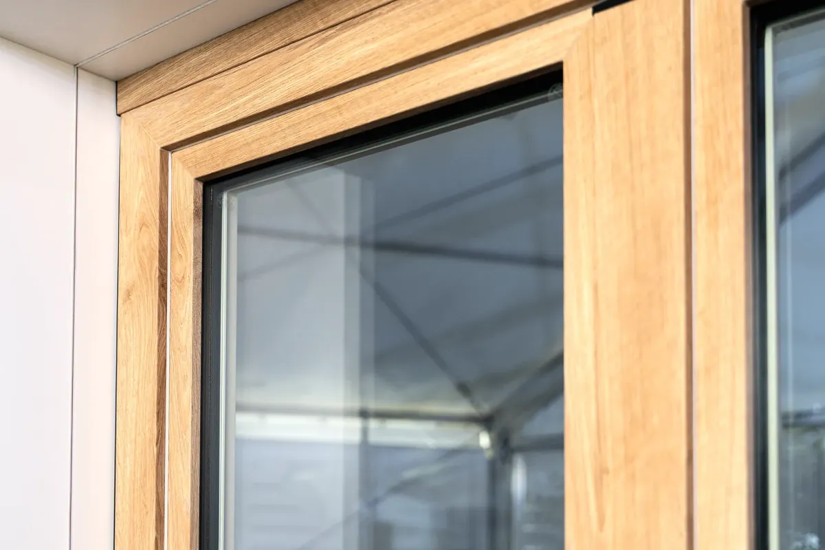 Fensterecke GEALAN-LINEAR mit Holzdekor-Folie, dahinter Glas (Herstellerbild GEALAN)