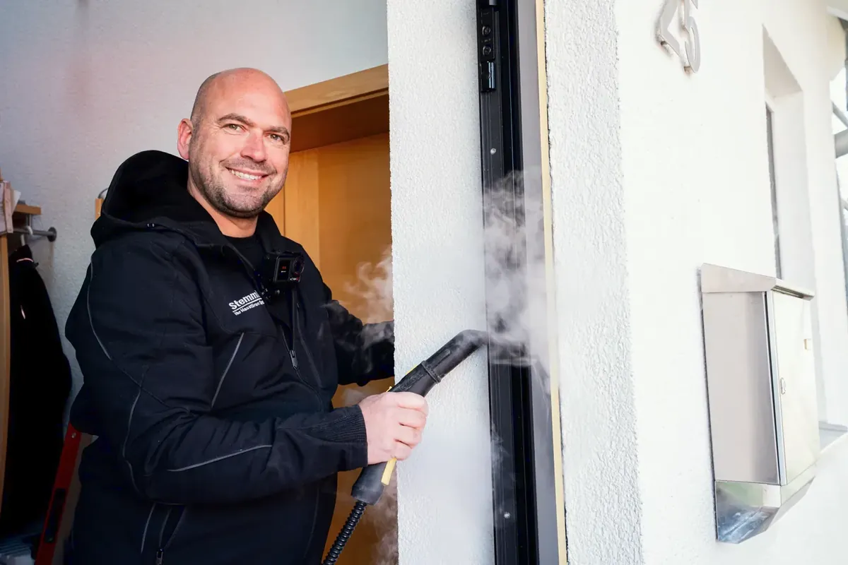 Marc Stemmler lächelt bei der Arbeit an einer Türzarge