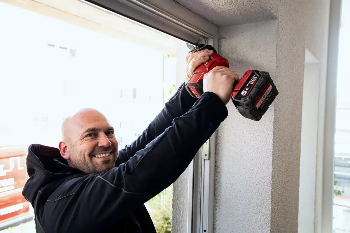 Marc Stemmler bohrt lächelnd am Rahmen einer neuen Haustür