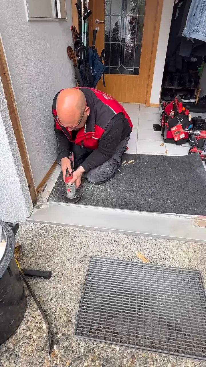 Marc Stemmler kniet an der Türschwelle und arbeitet an einer neuen Haustür
