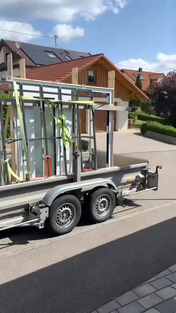 Anhänger mit neuen Haustüren vor einem Haus
