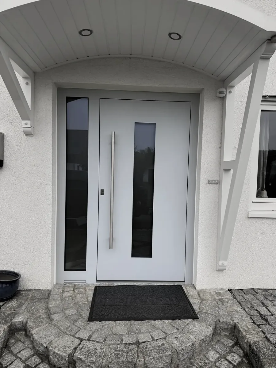 Hellgraue Haustür mit Glasstreifen unter einem Vordach